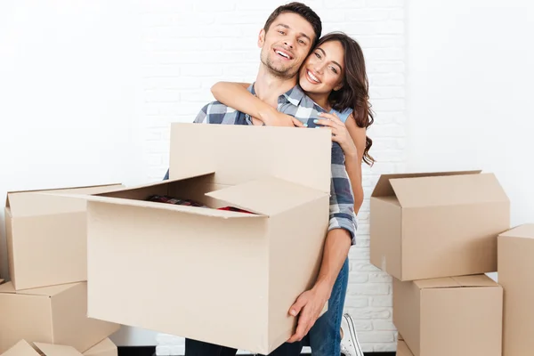 Smiling young couple carrying cardboard boxes and hugging — Stock Photo, Image