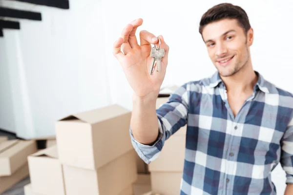 Lycklig man flyttar visar nycklar i sin nya lägenhet — Stockfoto