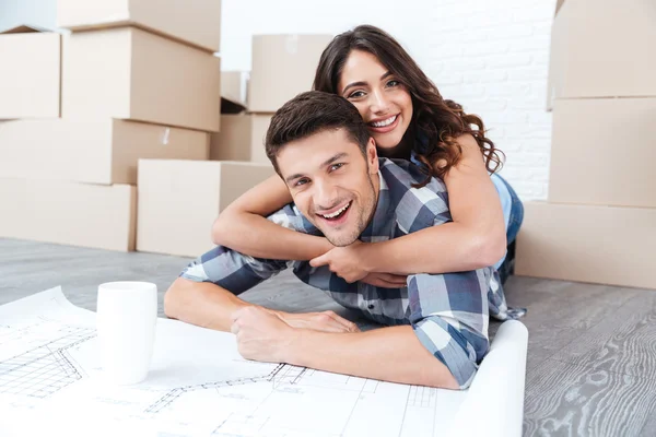 Glückliches Paar schaut sich neue Baupläne für Haus an — Stockfoto