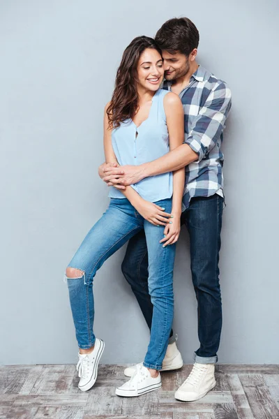 Pareja sonriendo y abrazándose sobre fondo gris —  Fotos de Stock