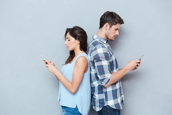 Cuplu în picioare unul la altul uitându-se la telefon — Fotografie, imagine de stoc