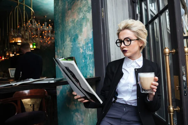 Retrato de cerca de la chica sentada en la cafetería con la revista — Foto de Stock