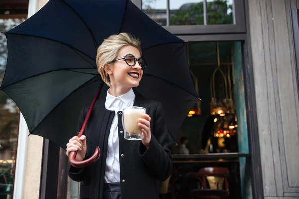 Joven mujer sonriente con paraguas y taza de café — Foto de Stock