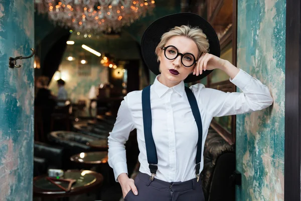 Relaxed stylish young woman in black hat and round glasses — Stock Photo, Image