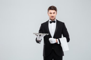 Ayakta ve boş tepsi tutarak smokin çekici uşak