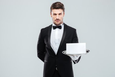 Smokin boş kartı tepsi üzerinde tutarak kendine güvenen genç uşak