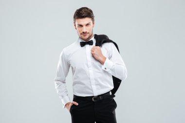 Ayakta ve ceketini tutan smokin harika genç adam