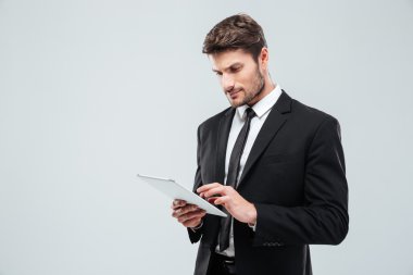 Ayakta ve tabet kullanarak konsantre genç işadamı