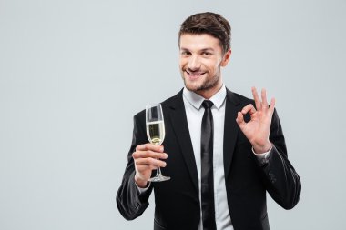 Şampanya içmek ve ok işaret gösteren neşeli genç işadamı