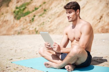 Sahilde tablet kullanan adam konsantre