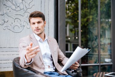 Gazete tutan ve açık bir şeye işaret eden işadamı