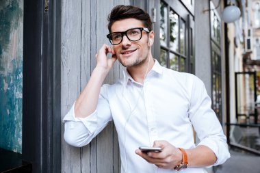 Yürüyüş ve smartphone--dan müzik genç adam gülümseyen