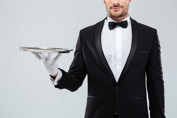 Closeup of waiter in tuxedo and gloves holding silver tray — Stock Photo, Image