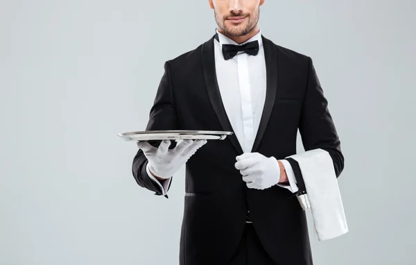 Waiter in tuxedo holding metal empty tray and napkin — Stock Photo, Image