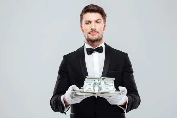 Attraktiver Butler im Smoking und Handschuhen, die Geld auf Tablett halten — Stockfoto