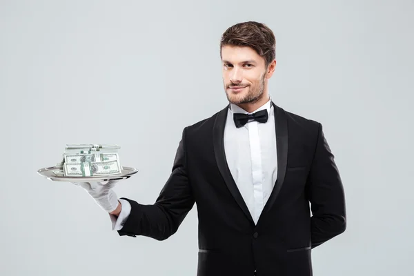 Nádherná butler ve smokingu stojí a drží tác s penězi — Stock fotografie