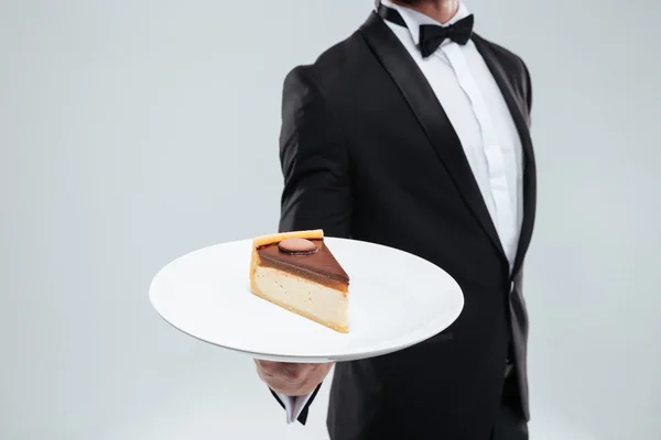 Σερβιτόρος σε σμόκιν κρατώντας πινακίδα με το κομμάτι του κέικ — Φωτογραφία Αρχείου