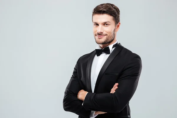 Smiling confident man in tuxedo standing with arms crossed — Stock Photo, Image