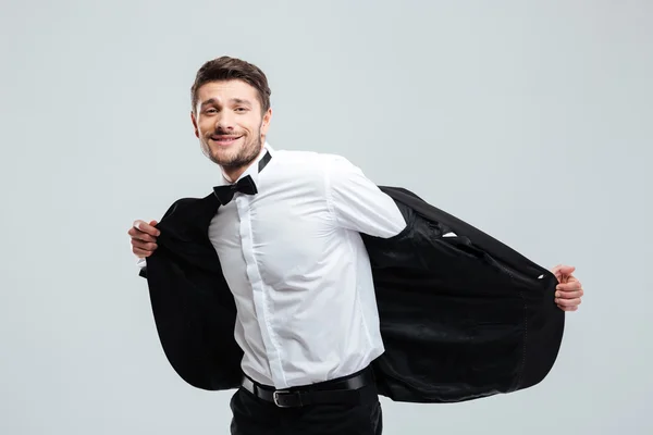 Cheerful man in tuxedo standing and taking off his jacket — Stock Photo, Image