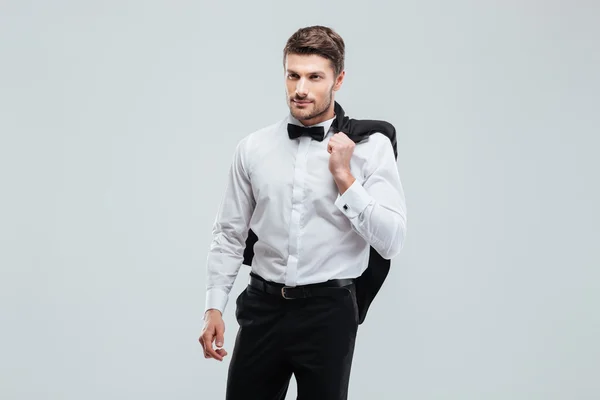 Handsome young man in tuxedo with bowtie holding his jacket — Stock Photo, Image