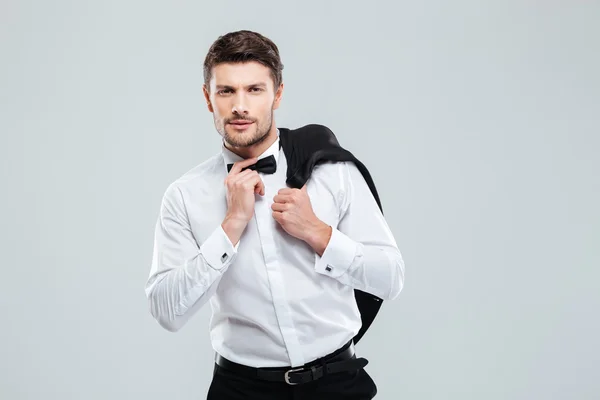 Hombre en esmoquin con corbata de pie y sosteniendo su chaqueta — Foto de Stock