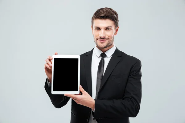 Уверенный молодой бизнесмен стоит и показывает чистый экран планшета — стоковое фото