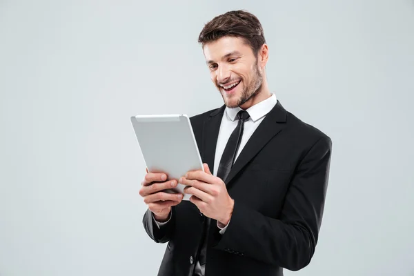 Vrolijke jonge zakenman met behulp van tablet en lachen — Stockfoto
