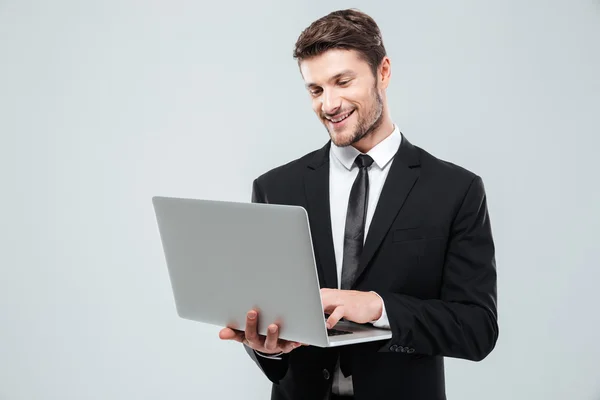 Fröhlicher junger Geschäftsmann lächelt und benutzt Laptop — Stockfoto