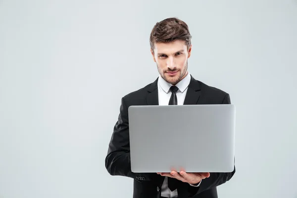 Joven hombre de negocios confiado en traje y corbata usando computadora portátil — Foto de Stock