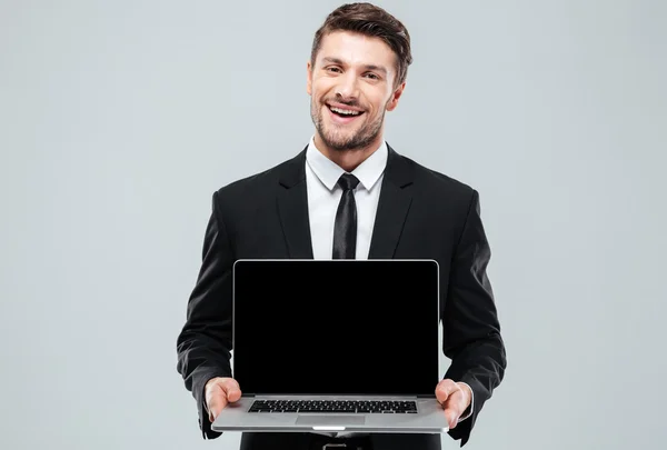 Happy attractive young businessman holding blank screen laptop — Stock Photo, Image