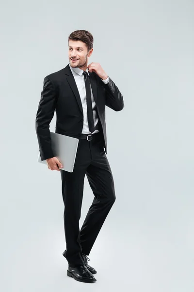 Full length of smiling young businesman with laptop — Stock Photo, Image