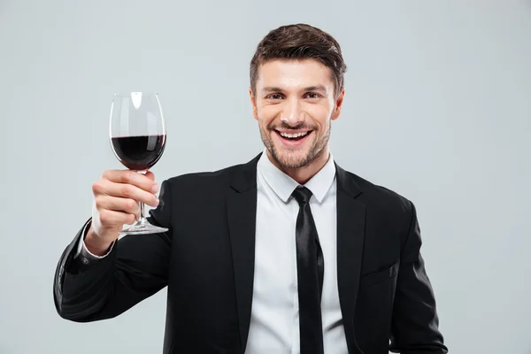 Cheeful young businessman smiling and drinking red wine — Stock Photo, Image