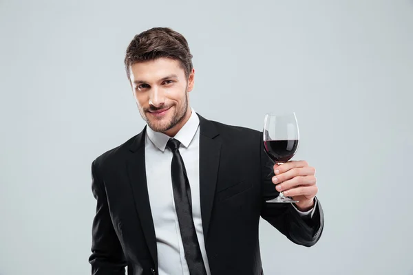 Χαμογελαστός νεαρός επιχειρηματίας κρατώντας το ποτήρι κόκκινο κρασί — Φωτογραφία Αρχείου