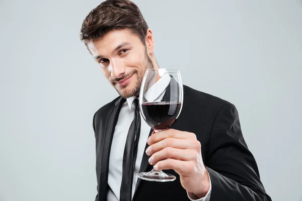 Yakışıklı genç gülümseyen ve elinde kadeh kırmızı şarap adam — Stok fotoğraf