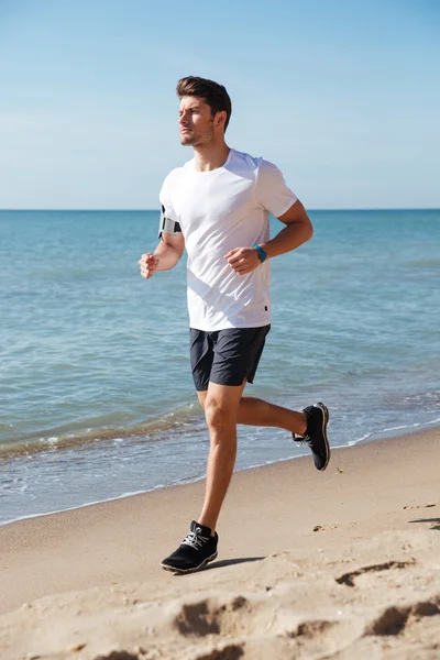 Koncentrované mladého sportovce zaběhat na pláži — Stock fotografie