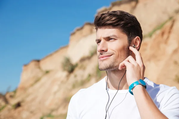 听音乐在海滩上使用耳机的运动员 — 图库照片