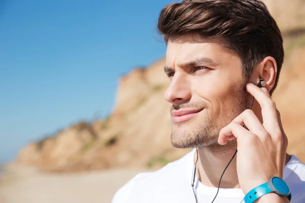 Uśmiechający się młodego sportowca, słuchania muzyki na plaży — Zdjęcie stockowe