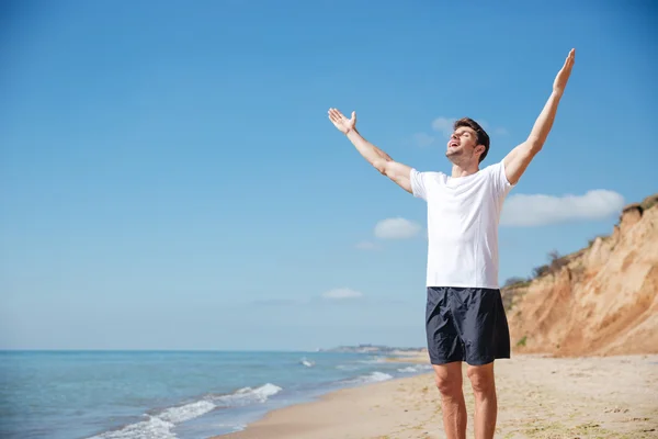 Cheerful man with outstretched arms standing on the beach