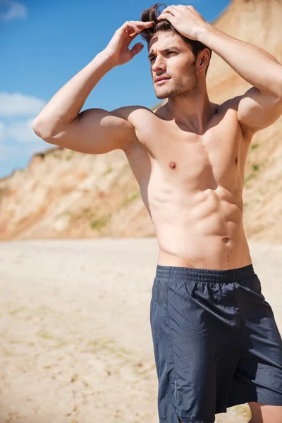 Atractivo joven sin camisa de pie en la playa —  Fotos de Stock