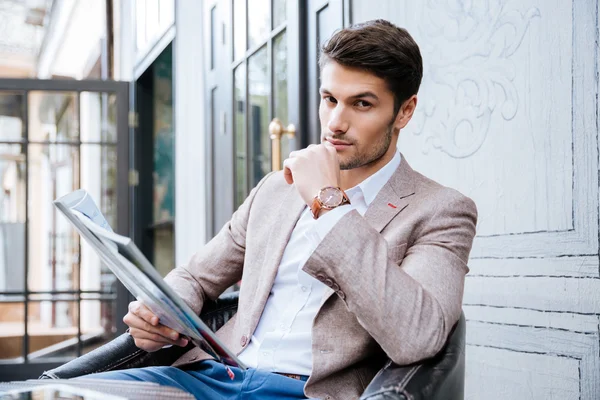 Młody przystojny biznesmen czytanie gazety w kawiarni — Zdjęcie stockowe