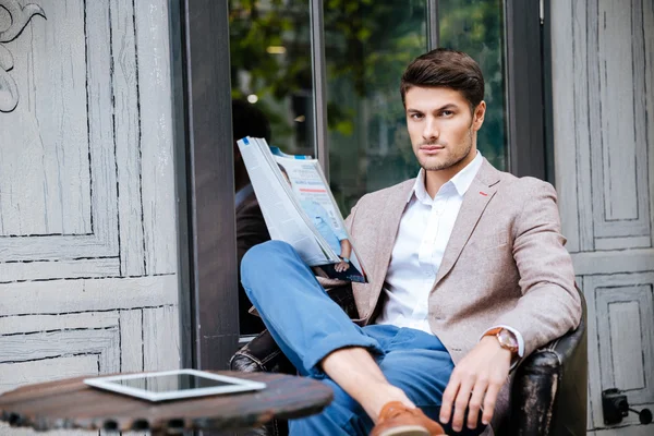 Σοβαρή νεαρός άνδρας ανάγνωση περιοδικό στην εξωτερική καφετέρια — Φωτογραφία Αρχείου