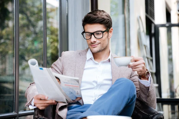 Schöner junger Mann mit Magazin trinkt Kaffee im Café — Stockfoto
