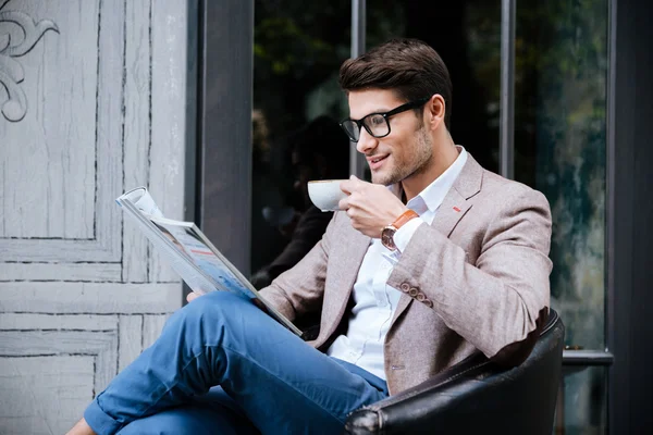 Lächelnder Mann trinkt Kaffee und liest Zeitschrift in Outdoor-Café — Stockfoto