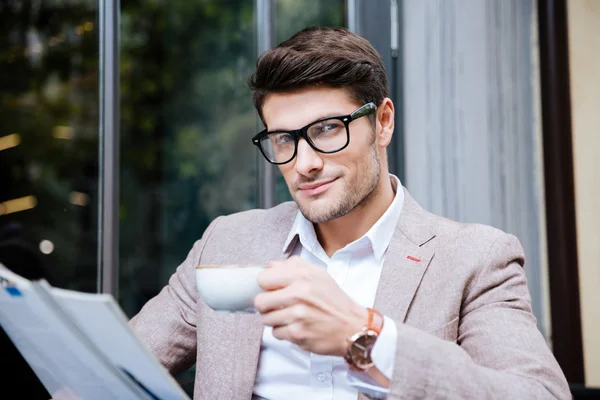 Attraktiver junger Mann in Gläsern trinkt Kaffee in Outdoor-Café — Stockfoto