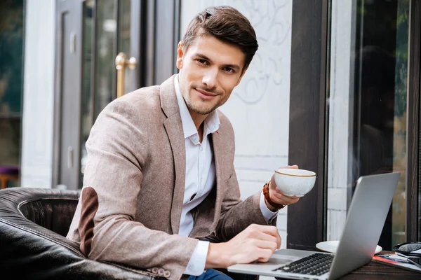 Hombre con portátil sentado y beber café en la cafetería al aire libre — Foto de Stock