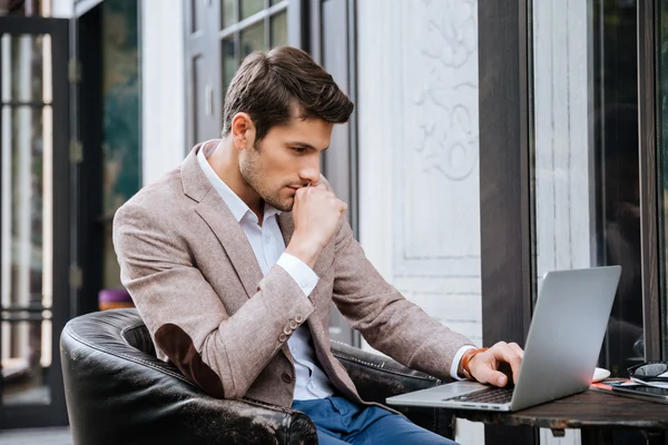 Homme d'affaires travaillant sur un ordinateur portable tout en étant assis dans un café — Photo