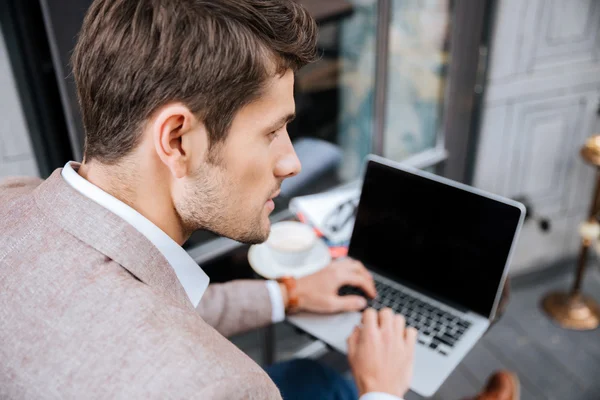 Nahaufnahme eines seriösen Geschäftsmannes mit modernem Laptop im Café — Stockfoto