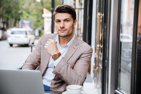 Hombre de negocios serio utilizando el ordenador portátil moderno en la cafetería —  Fotos de Stock