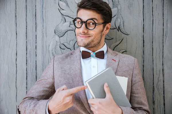 Söt rolig människa i runda glasögon pekar på boken — Stockfoto