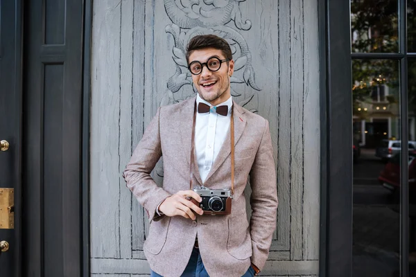 Smiling man in funny round glasses holding vintage photo camera — Stock Photo, Image